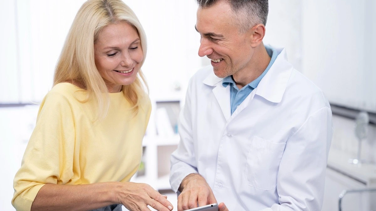 Zahnarzt der Patientin etwas auf Tablet zeigt