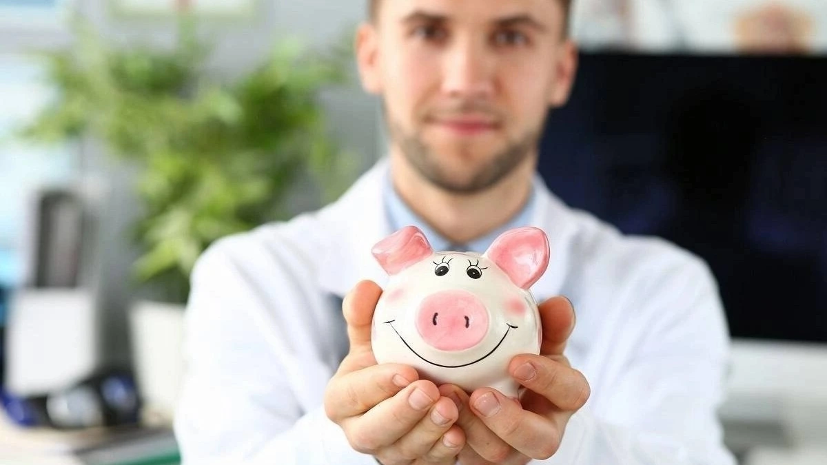 ZFA mit Tisch im Hintergrund. Dieser hält Sparschwein in die Kamera.