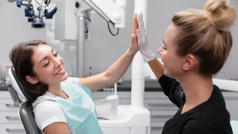 ZFA und Patientin geben sich High Five im Behandlungszimmer – Online-Kurs effektive Patientenkommunikation und Motivation in der Prophylaxe | Spitta Akademie