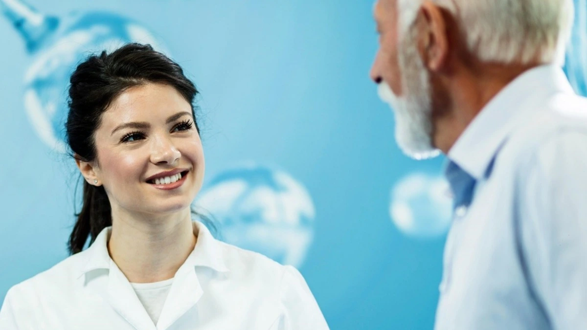 Zahnärztin im Kittel lächelt älteren Patienten an – Online-Kurs erfolgreiches Patientenmanagement Grundlagen | Spitta Akademie