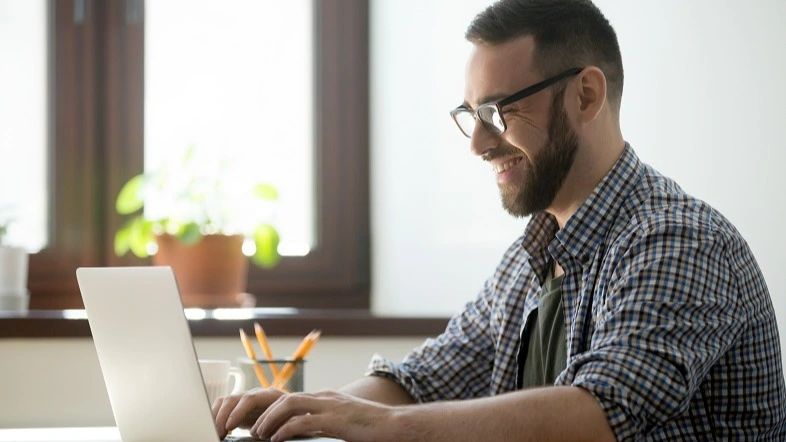 Mann mit Brille lächelt beim Lernen am Laptop – Online-Kurs EU Medizinprodukteverordnung MDR Zahnarztpraxis | Spitta Akademie