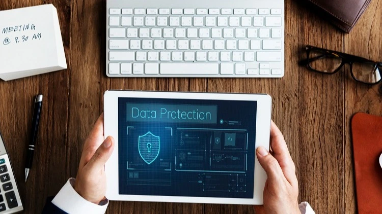 Hände halten Tablet mit Data-Protection-Anzeige am Schreibtisch – Online-Kurs Datenschutz und Schweigepflicht in der Zahnarztpraxis | Spitta Akademie