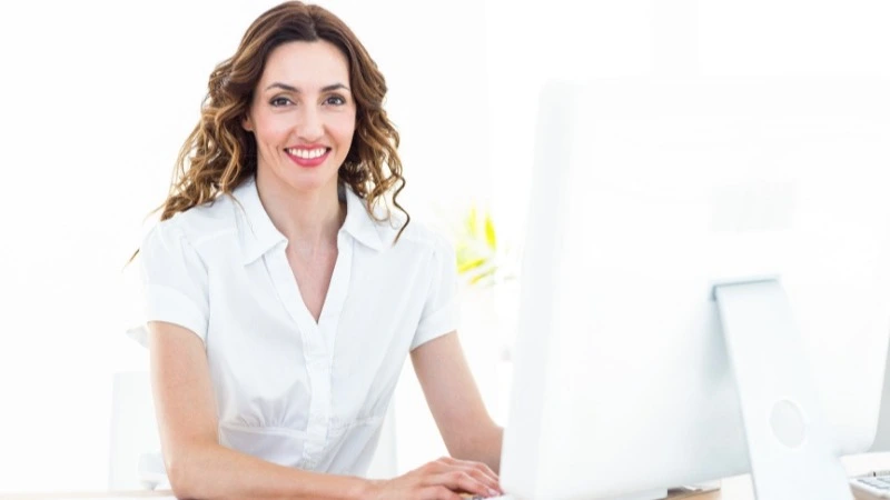 Frau lächelt am PC im Büro – Infoveranstaltung Online-Lehrgang Praxismanager Zahnarztpraxis IHK | Spitta Akademie